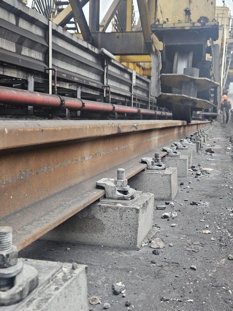 微信图片 Heavy-duty bolted rail clip installation on a shipyard gantry crane track showing the clip, sole plate, and bolt assembly. 