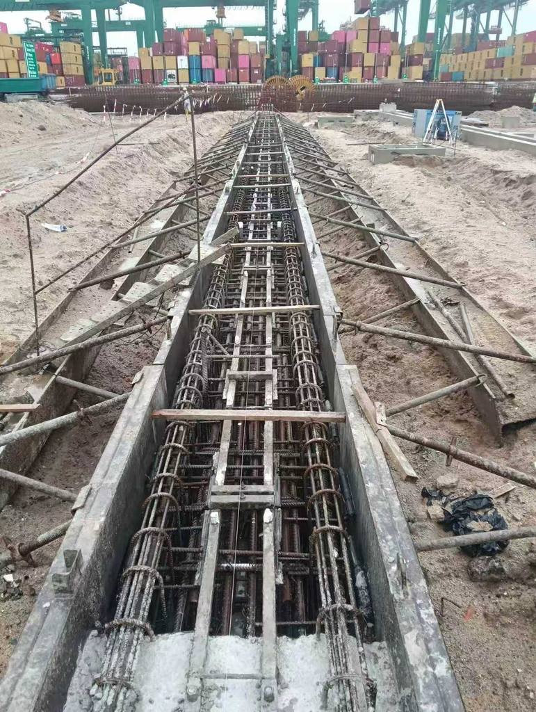 Reinforcement cage and formwork for cast‑in‑situ crane rail foundation beam at container terminal, before grout pouring