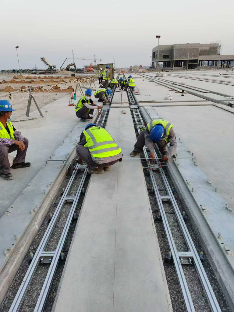 Workers carrying out precise alignment and adjustment of crane rails prior to secondary grouting at container terminal yard